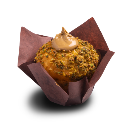 Muffin coberto com pistácio triturado, com um redemoinho de cobertura de caramelo, em forma tulipa castanha.