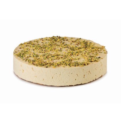 Disco redondo de halva claro coberto com pistácio picado, textura densa e esfarelada, em fundo branco.