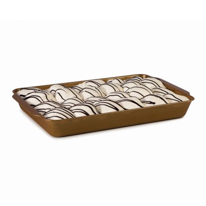 Filas de pastéis com cobertura branca e linhas de chocolate negro, dispostos num tabuleiro dourado rectangular
