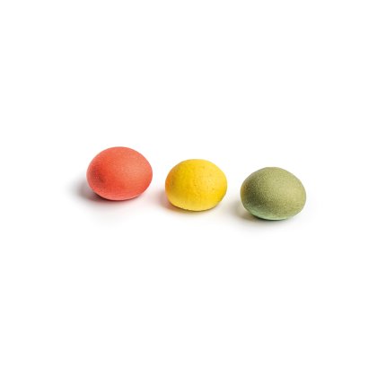 Três doces redondos e texturados nas cores vermelho, amarelo e verde, alinhados sobre fundo branco.