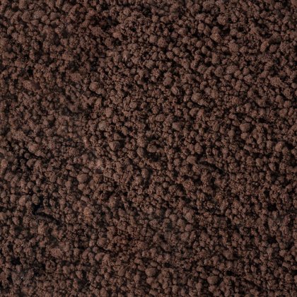 Plano aproximado de superfície castanho-escura e esfarelada, lembrando terra grossa ou borras de café.