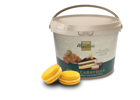 Balde bege de creme para barrar Master Martini Gran Caravella junto a dois macarons amarelos e um doce recheado.