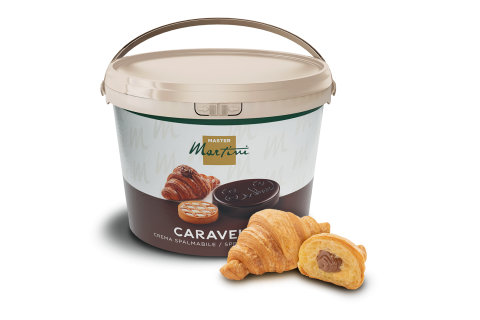 Balde beige de crema de chocolate para barrar Master Martini Caravel junto a dois croissants, um com chocolate.