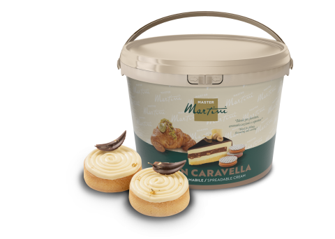 Balde grande de creme para barrar Master Martini ao lado de dois pastéis com raspas de chocolate e flocos dourados.