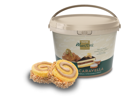 Balde grande de creme para barrar Master Martini Caravella ao lado de dois rolos de pão de ló com nozes e recheio cre...