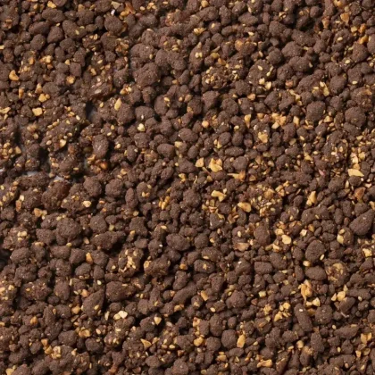 Plano aproximado de uma mistura castanha escura esfarelada com frutos secos picados, textura semelhante a crumble de ...